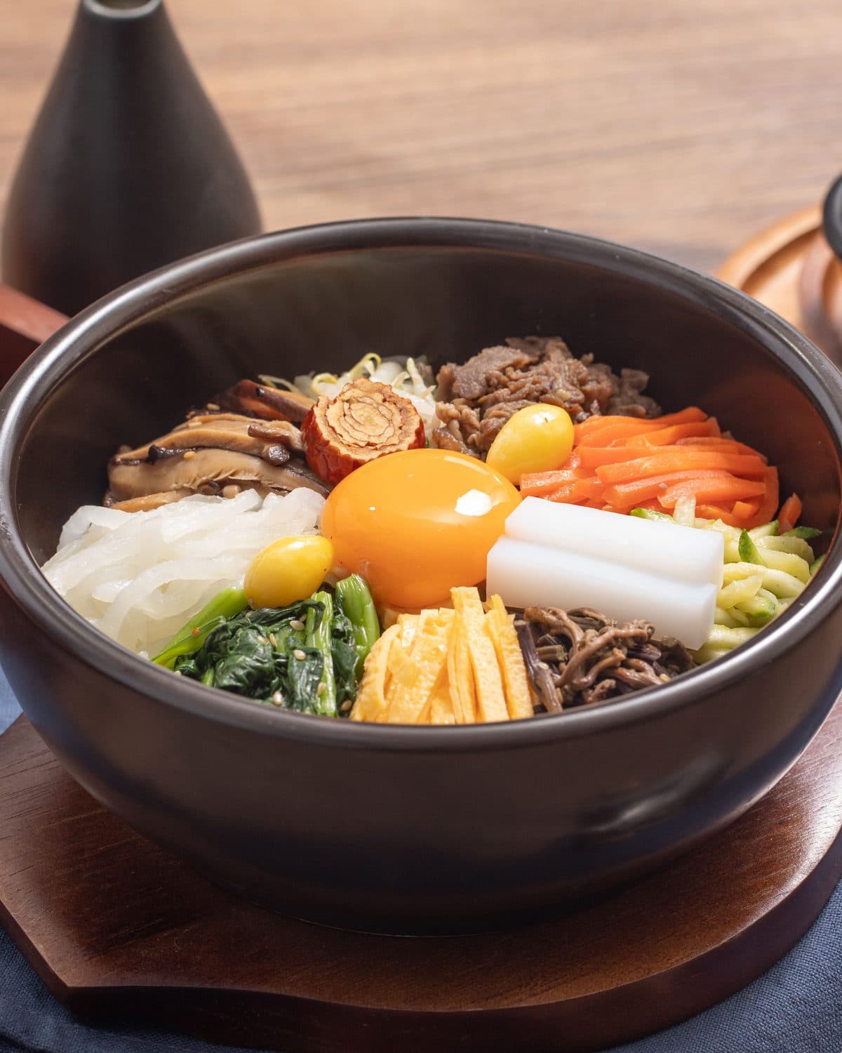 Dolsot bibimbap in a stone bowl, the yolk set in the middle