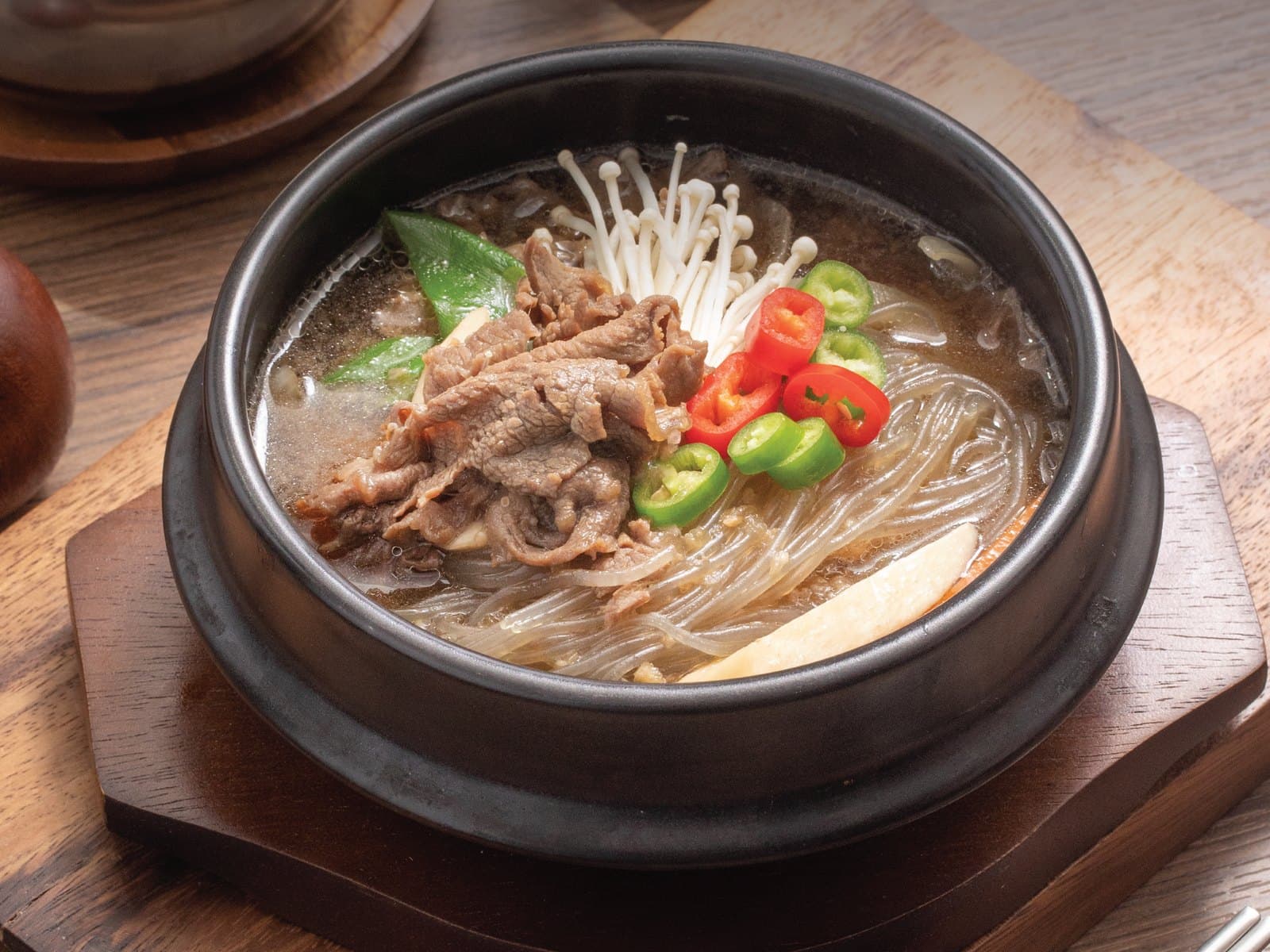 Beef and glass-noodle soup simmering in a stone bowl