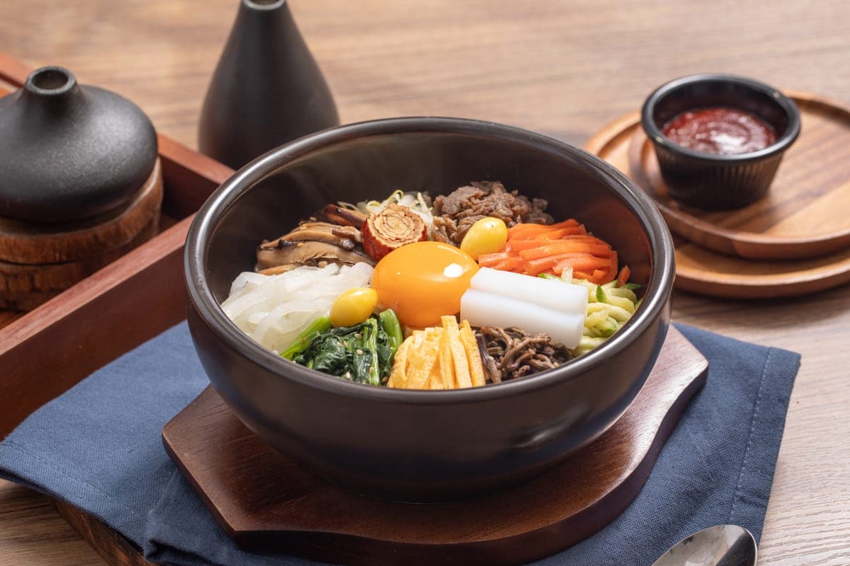 Dolsot bibimbap in a stone bowl, crowned with an egg yolk