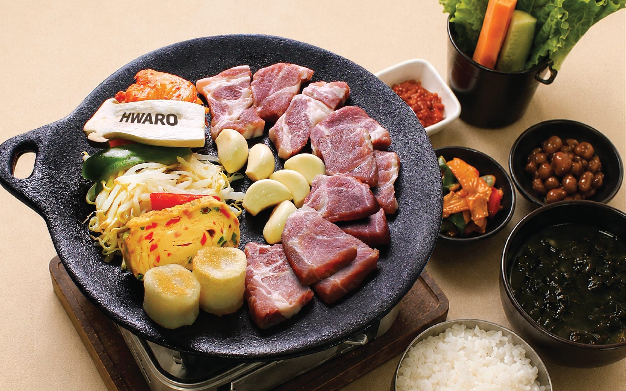 Moksal, garlic and rice cake set on the Hwaro griddle, with banchan, rice and seaweed soup