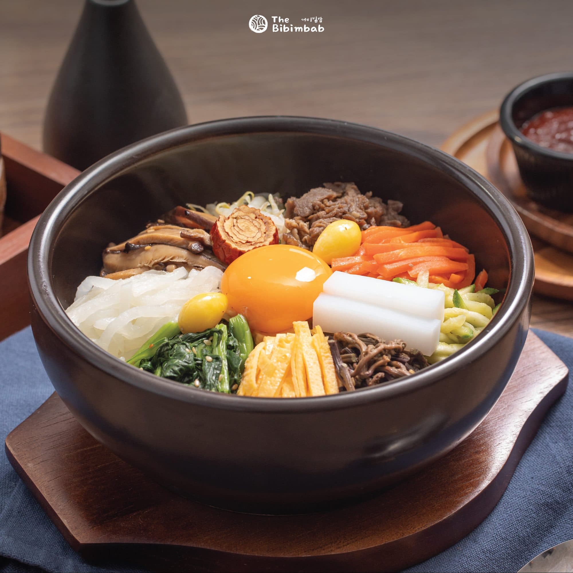 Dolsot bibimbap in a hot stone bowl with vegetables, beef and an egg yolk