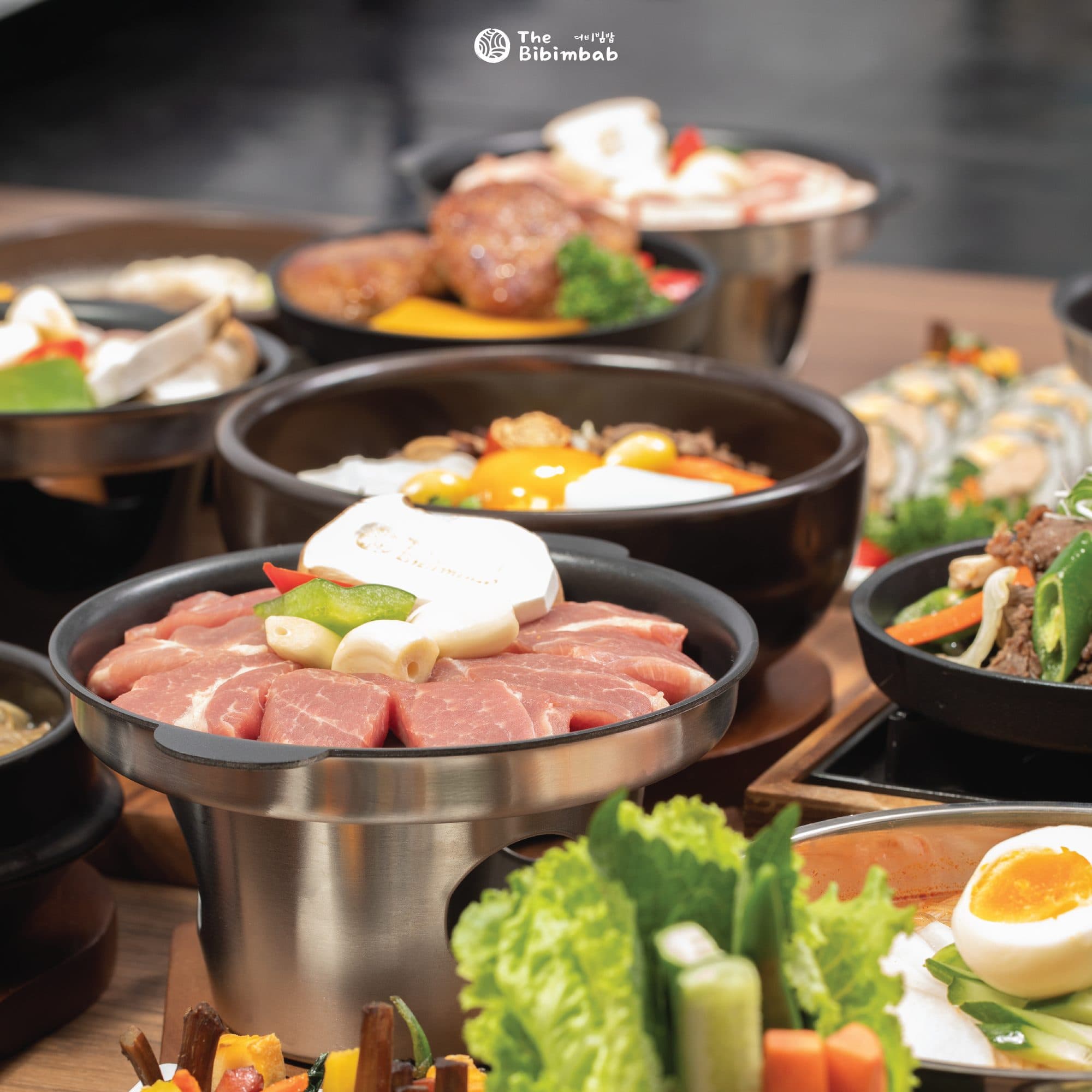 Dolsot bibimbap, a griddle pan of pork and side dishes set across one table